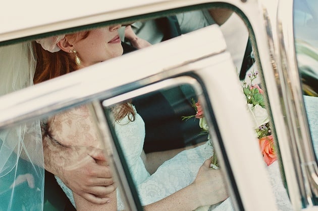 A bride in a car holding a bouquet