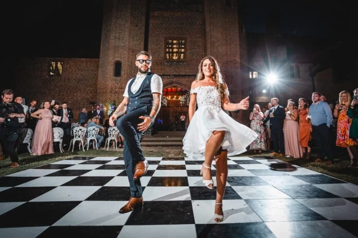 A newly wed couple dancing on a chequered floor