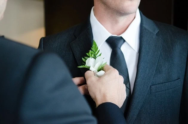 Best man adjusting groom's button hole