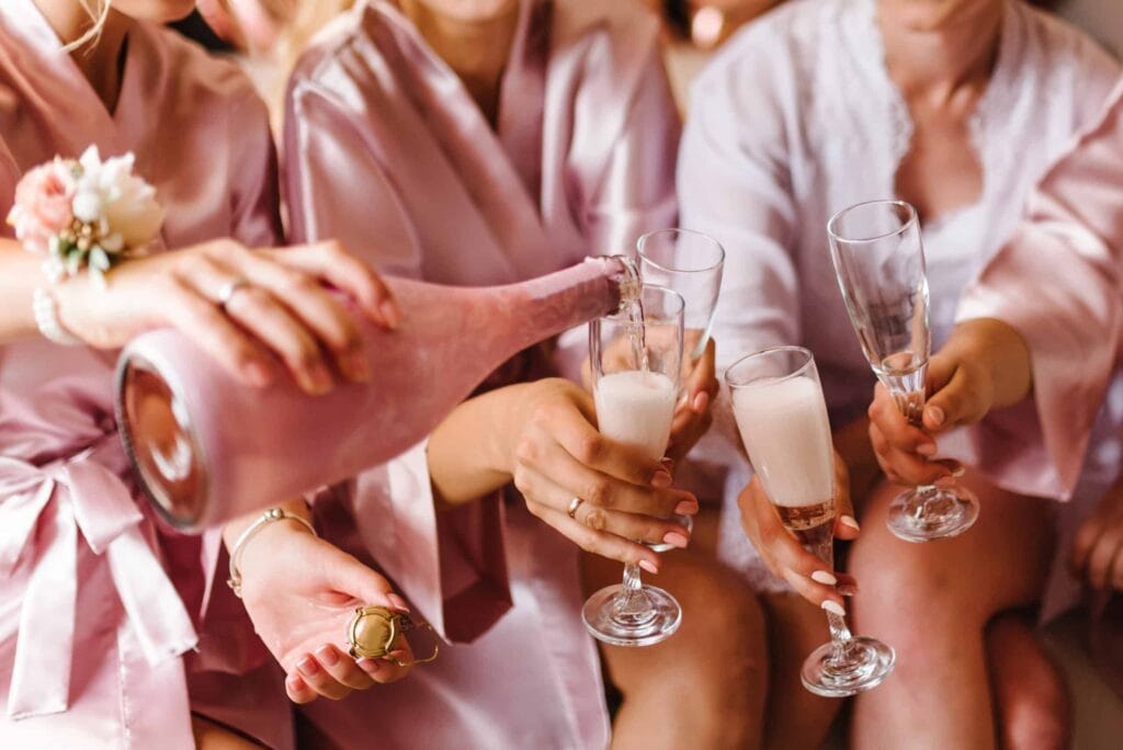 Elegant bridal party toasting with champagne at a country house wedding, showcasing intimate celebration in a luxurious estate setting.