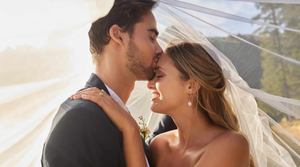 A groom kissing a bride's forehead